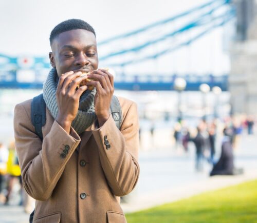 A man eating a sandwich by London Bridge - London has been named the most vegan-friendly city