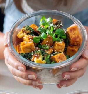 bowls of freshly prepared orange tofu and broccoli, one being held by the recipe developer from Plant Baes