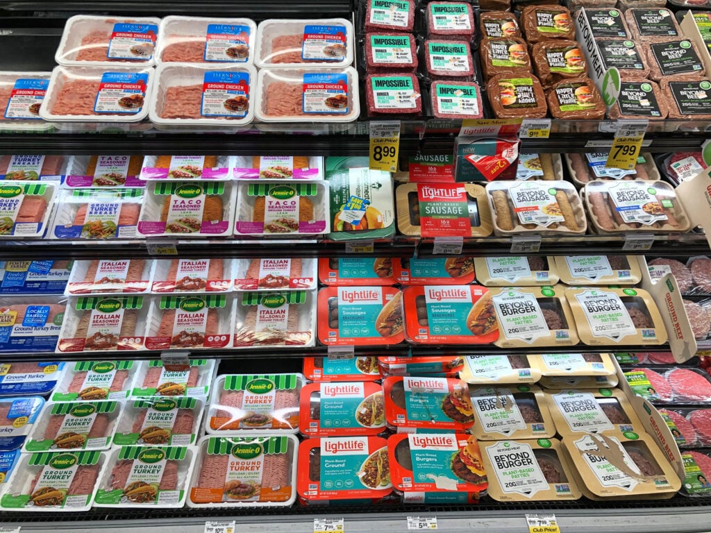 Vegan meat products next to animal-based turkey products in a supermarket